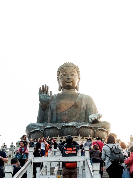 Scene showing people passing The Tian Tan Buddha statue in Hong Kong