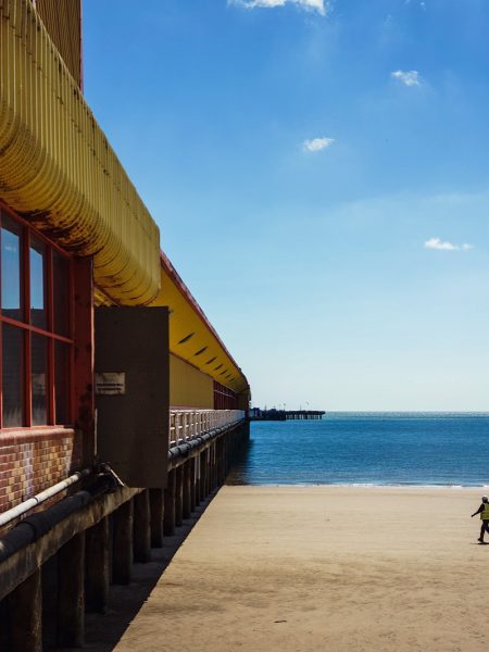 Man walking on the beach towards the underside of the pier