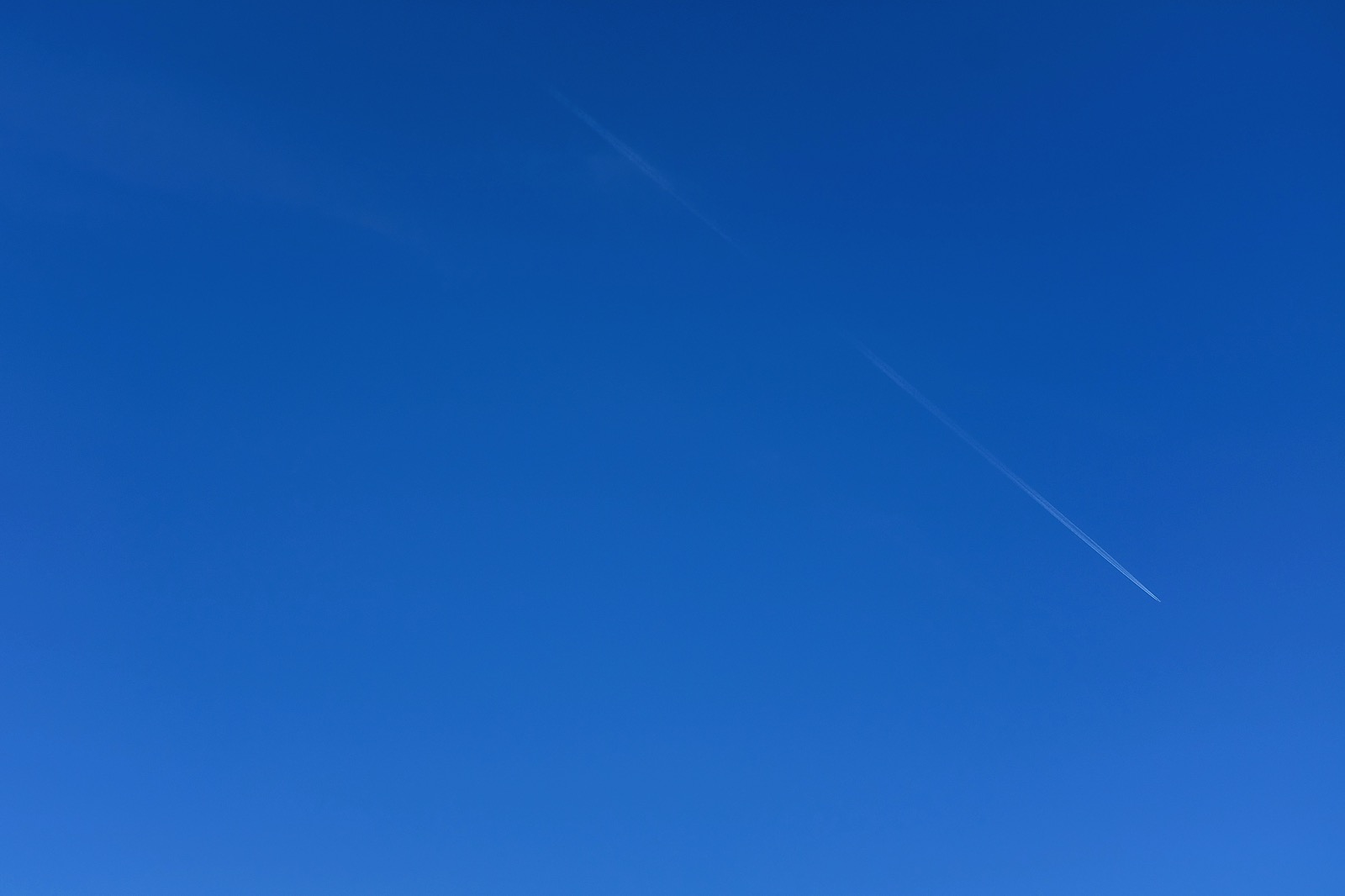 airplane trail against bright blue sky