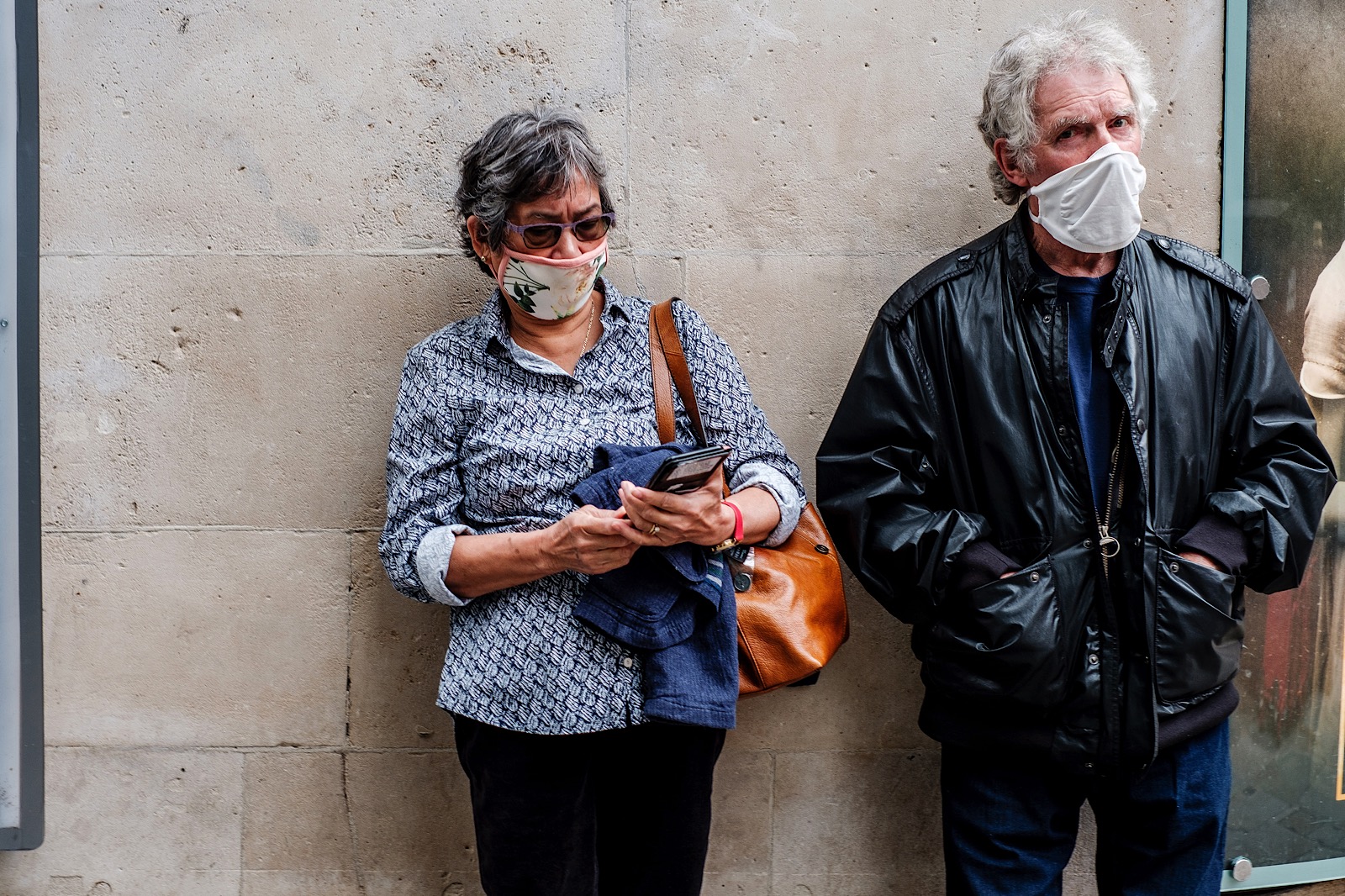 man and woman waiting in line wearing masks