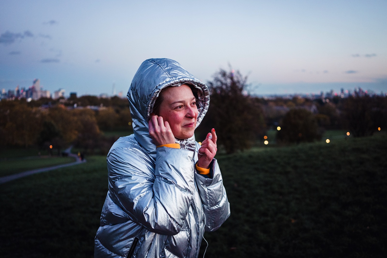 women wearing silver puffer jacket putting in headphones