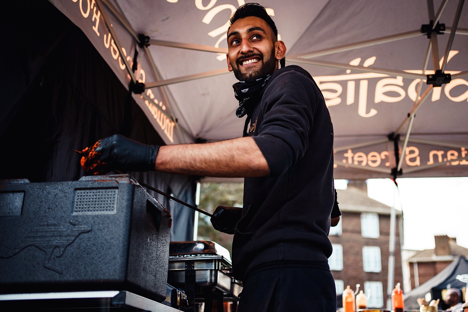 man preparing food outside grinning