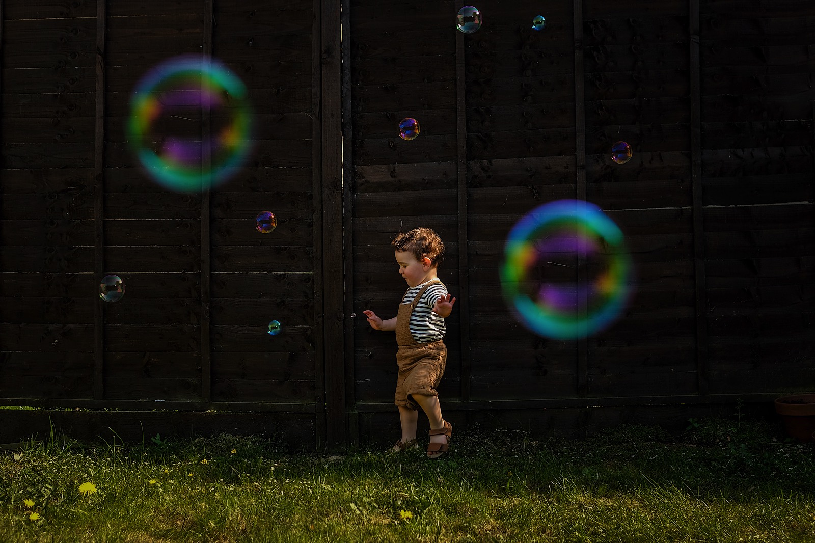 young child chasing bubbles in garden