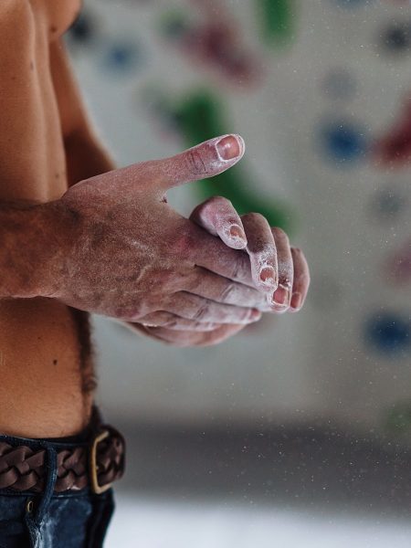 Topless Man rubbing chalk on hands in rock climbing centre